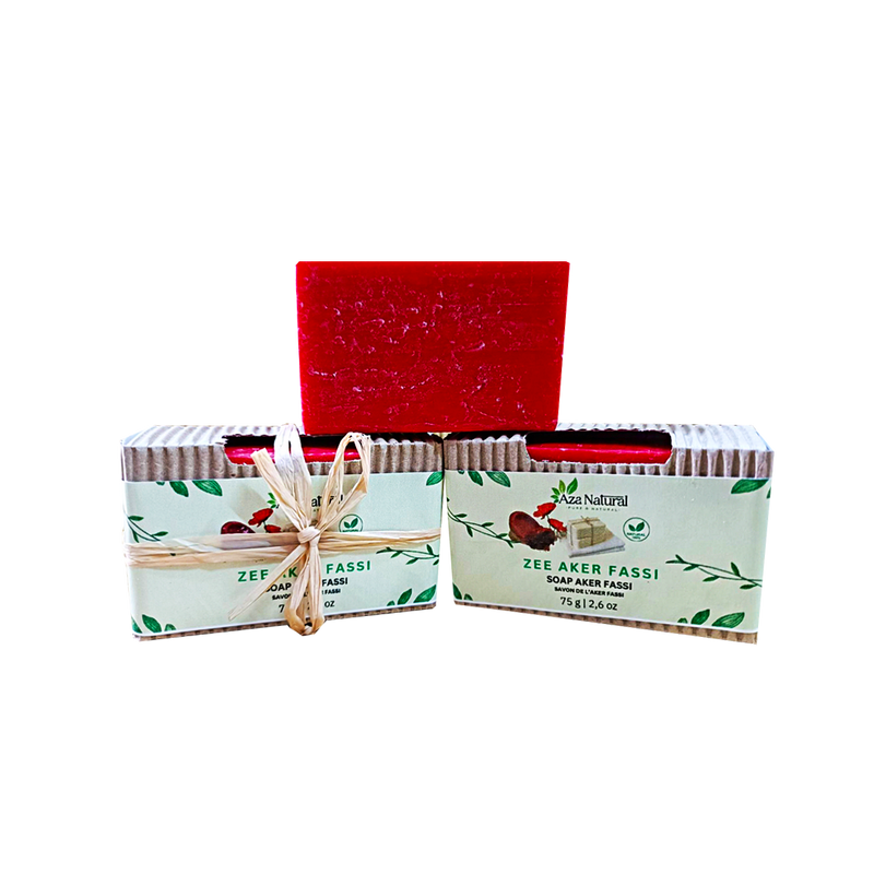 Rotes Stück Aker Fassi Seife von Aza Natural, ausgepackt auf zwei Banderolen aus Wellpappe