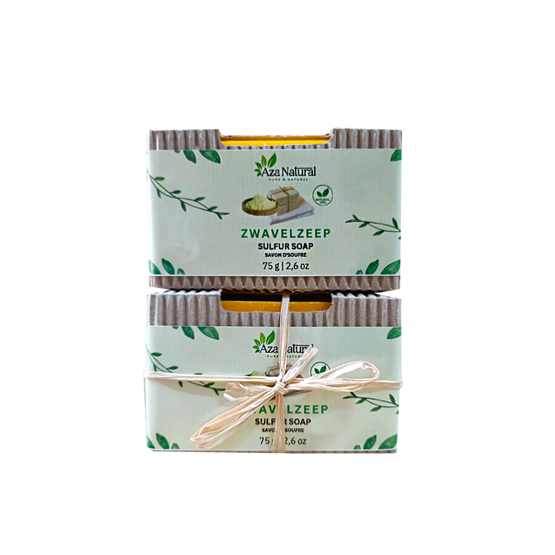 Zwei Stücke Schwefelseife von Aza Natural übereinander, in Banderolen aus Wellpappe, eines mit Bastschleife